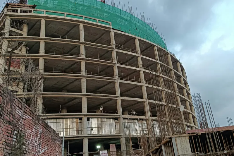 Multi-storey reinforced concrete commercial building under construction, with the frame complete and slab edges exposed.