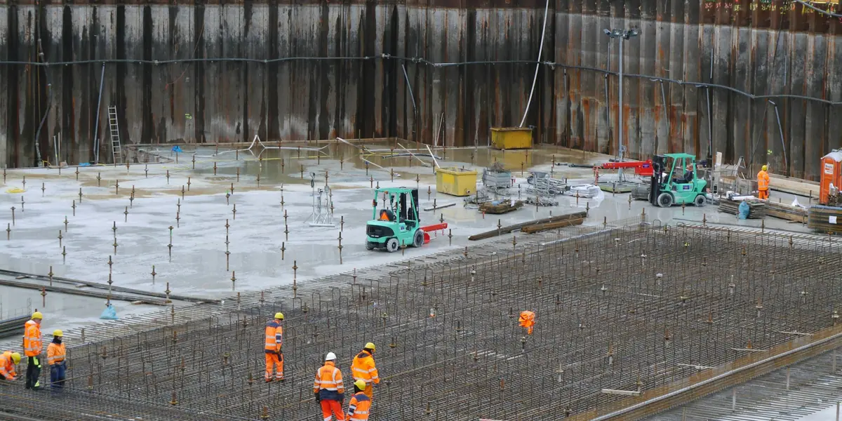 Site crew fixing steel reinforcement mesh across a large raft foundation ahead of the concrete pour.