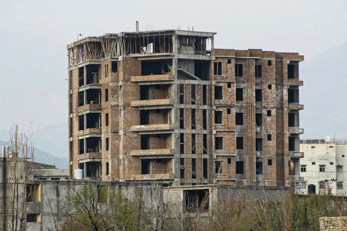 Multi-storey brick and concrete residential building at grey structure stage, with frame complete, brick infill walls up and plaster not yet started.