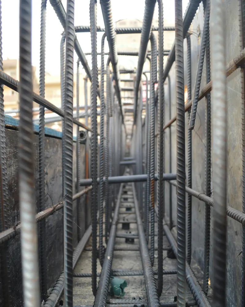 Vertical reinforcement cage of a concrete column, with main bars and closely spaced ties, viewed from below inside the shuttering.