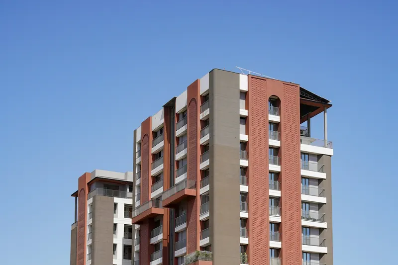 Completed low-rise apartment blocks with brick and render façades, balconies and a clear sky behind.