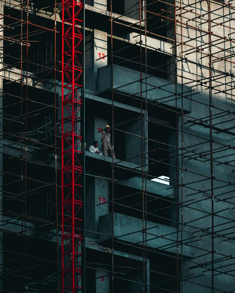 Scaffolding erected against the full height of an existing building while work proceeds on the upper floors.