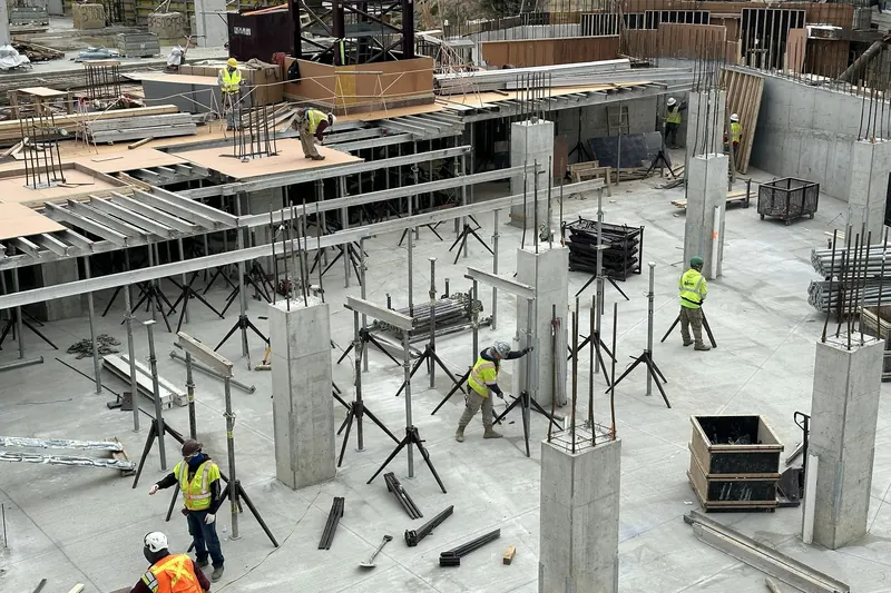 Large ground slab under construction with props, formwork tables and reinforcement laid out across an open industrial floor plate.